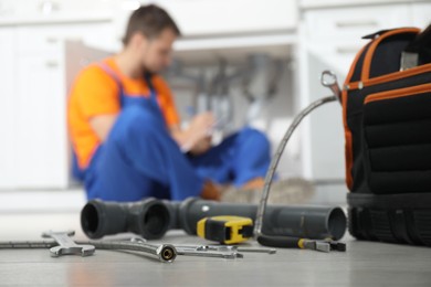 Professional plumber fixing piping system at home, focus on tools