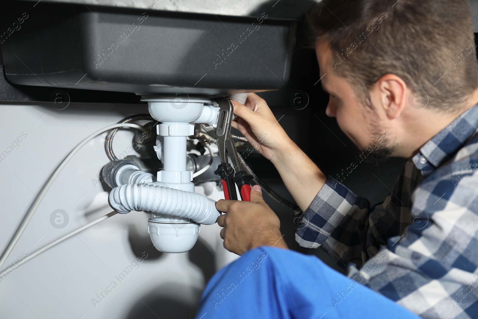 Photo of Professional plumber fixing piping system at home, closeup