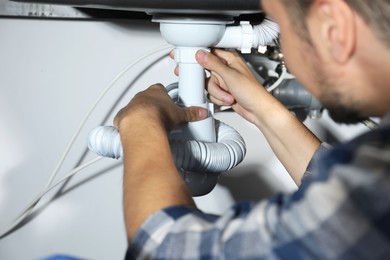 Professional plumber fixing piping system at home, closeup