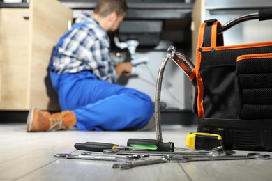 Photo of Professional plumber fixing piping system at home, focus on tools