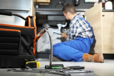 Photo of Professional plumber fixing piping system at home, focus on tools