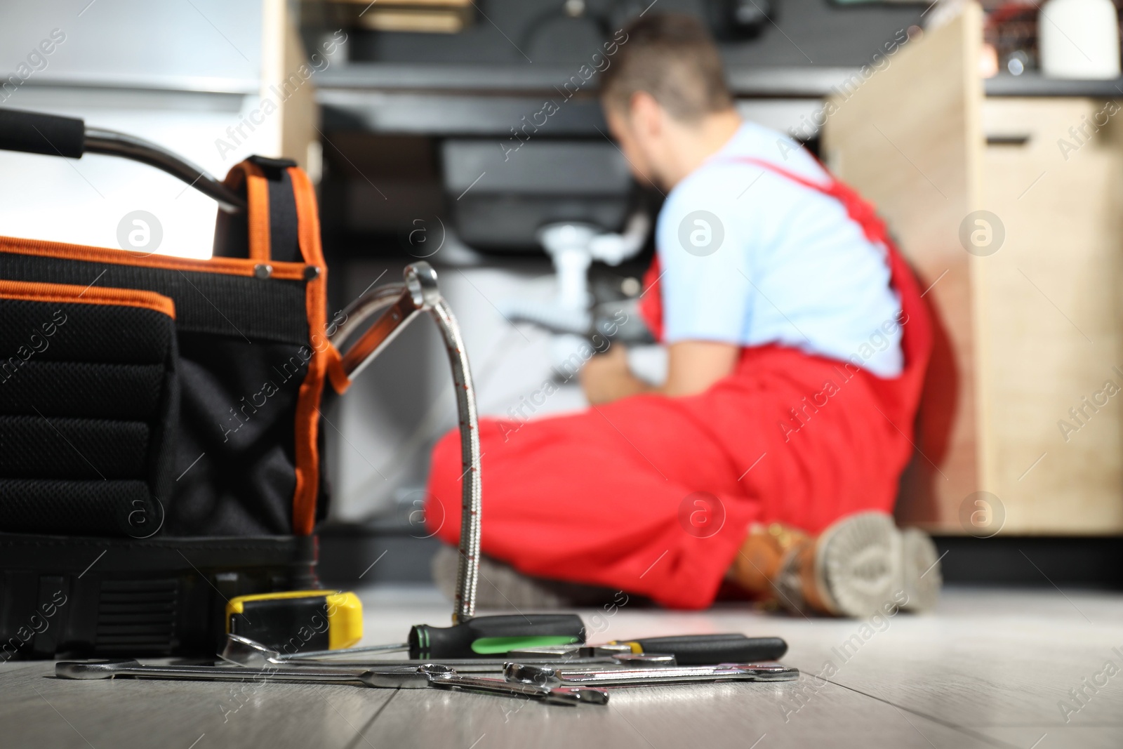 Photo of Professional plumber fixing piping system at home, focus on tools