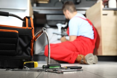 Photo of Professional plumber fixing piping system at home, focus on tools