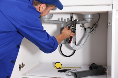 Professional plumber fixing piping system at home