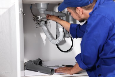 Professional plumber fixing piping system at home