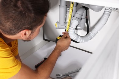 Photo of Professional plumber fixing piping system at home, closeup