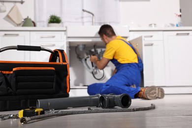 Photo of Professional plumber fixing piping system at home, focus on tools