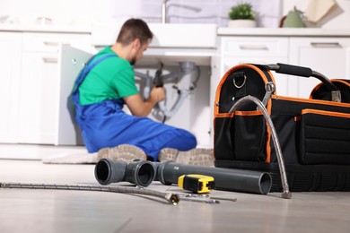 Photo of Professional plumber fixing piping system at home, focus on tools