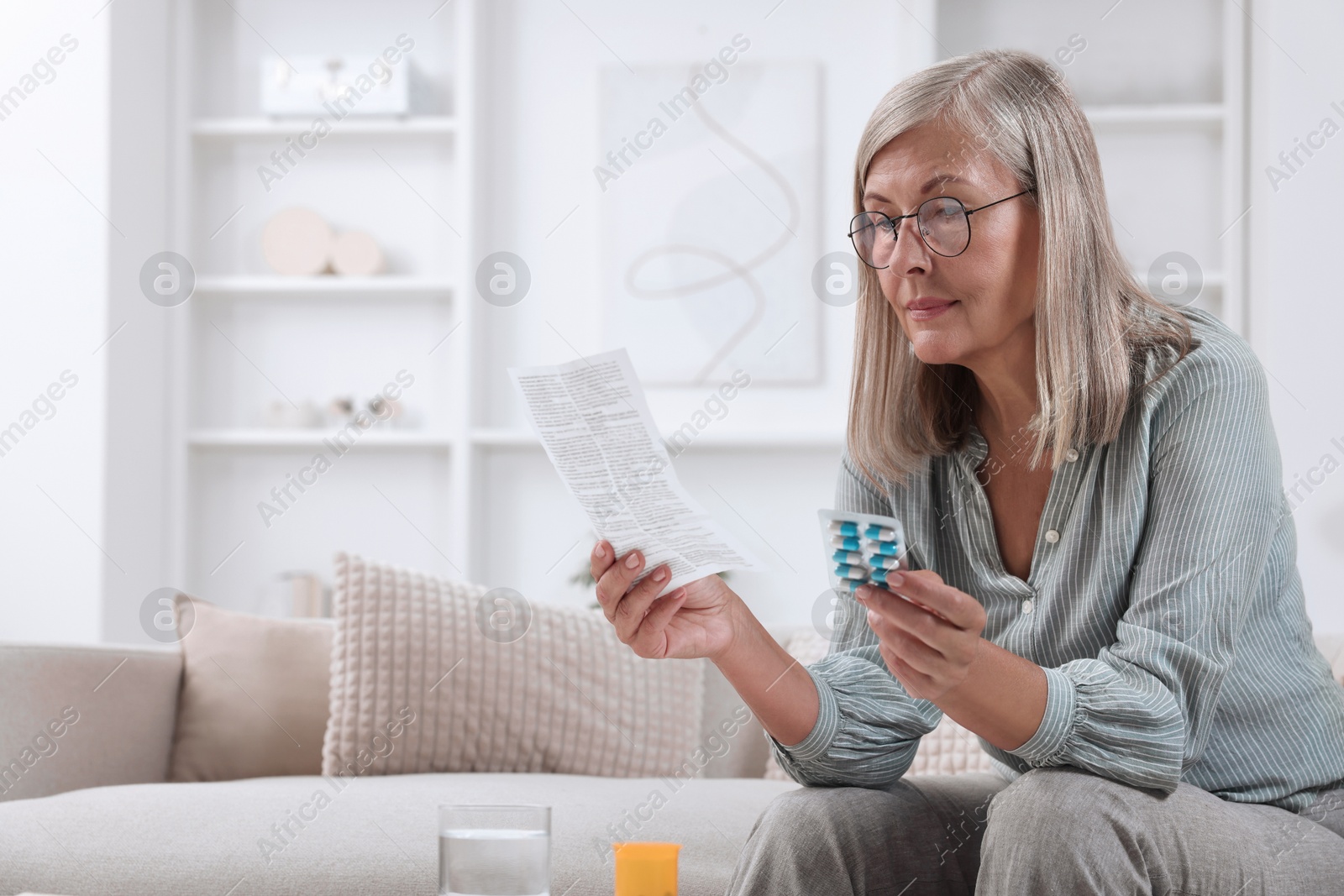 Photo of Senior woman with pills reading medicine instruction at home