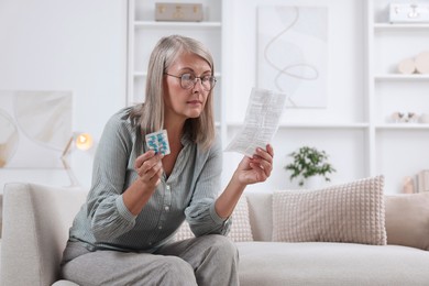 Photo of Senior woman with pills reading medicine instruction at home