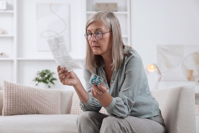 Photo of Senior woman with pills reading medicine instruction at home