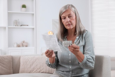 Senior woman with pills reading medicine instruction at home