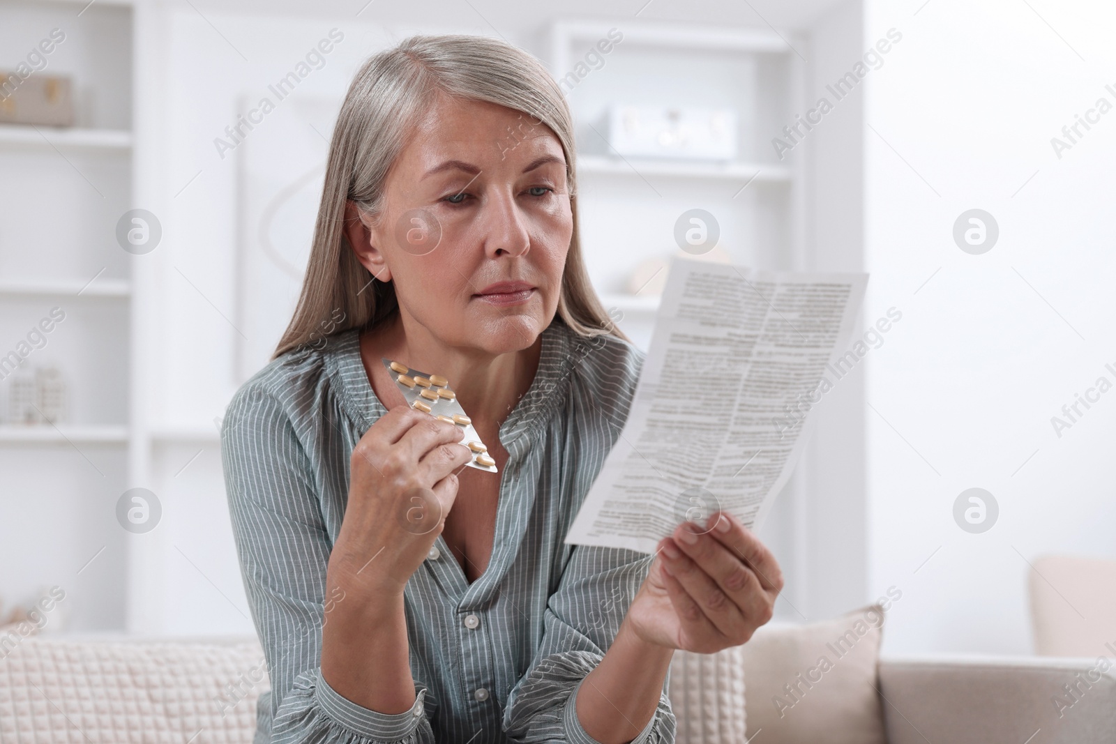 Photo of Senior woman with pills reading medicine instruction at home