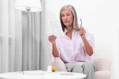 Photo of Senior woman reading medicine instruction in armchair at home