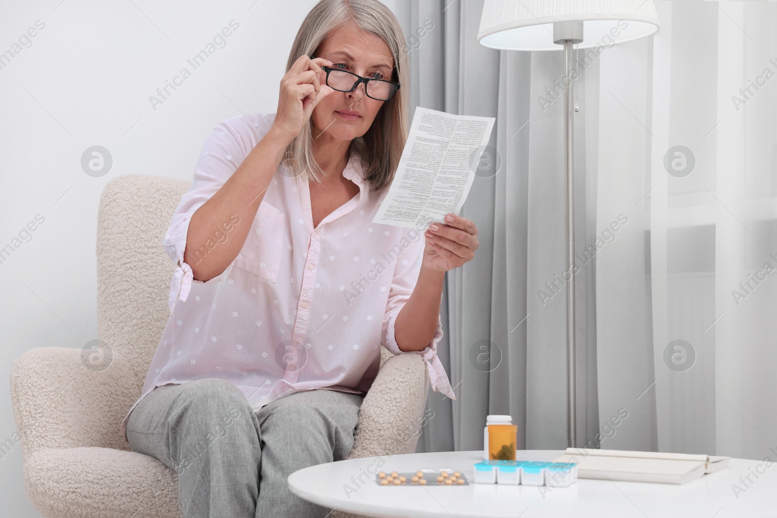 Photo of Senior woman reading medicine instruction in armchair at home