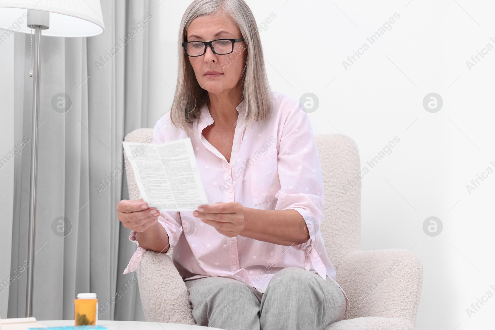 Photo of Senior woman reading medicine instruction in armchair at home