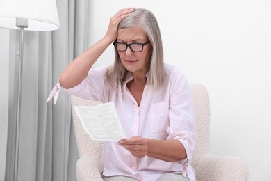 Photo of Senior woman reading medicine instruction in armchair at home