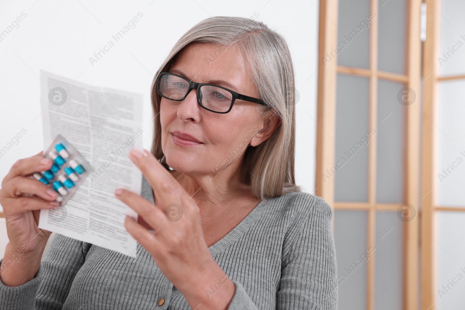 Photo of Senior woman with pills reading medicine instruction at home