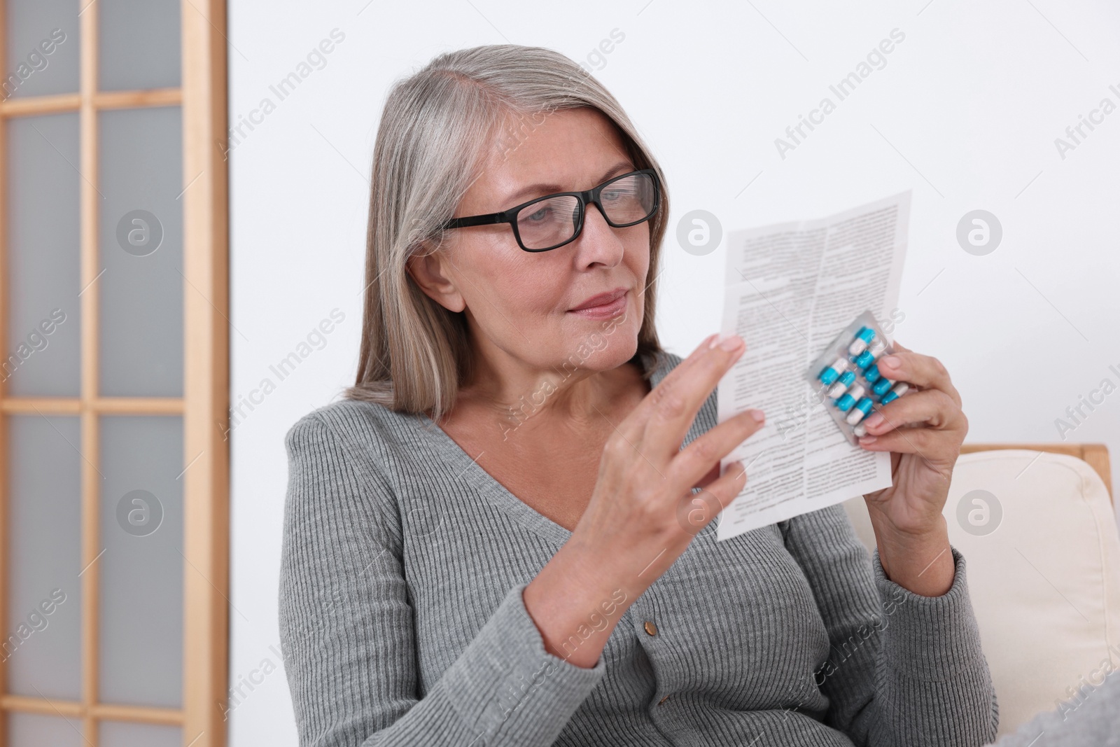 Photo of Senior woman with pills reading medicine instruction at home