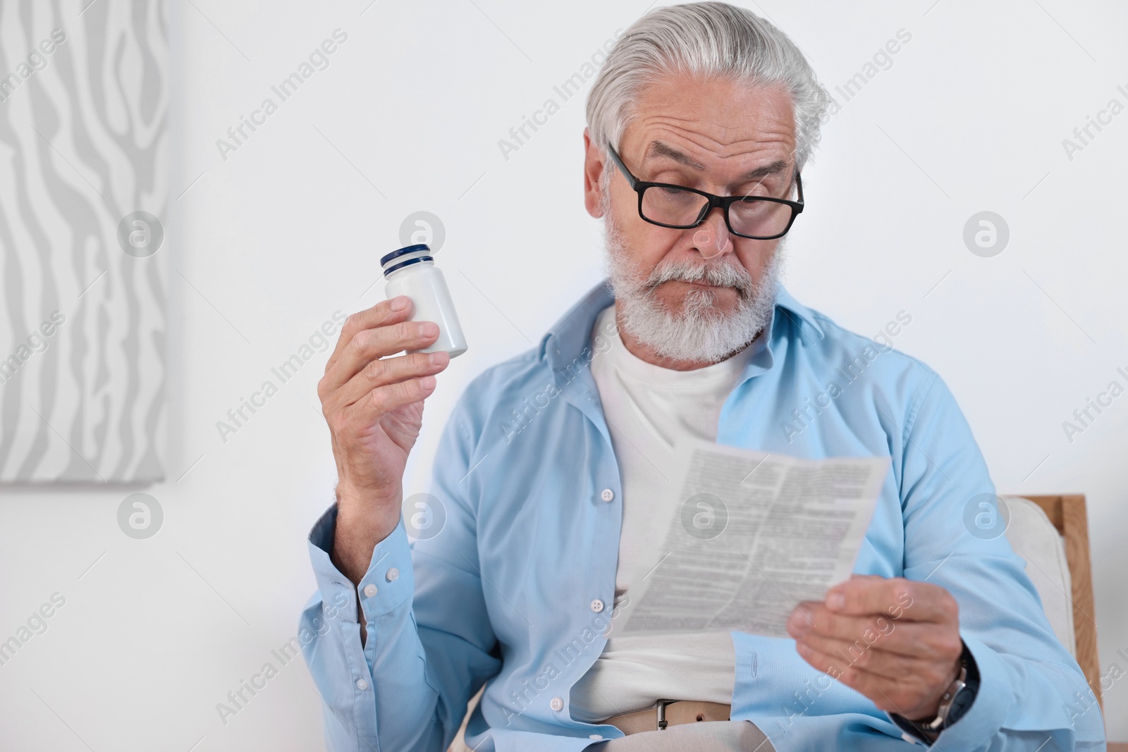 Photo of Senior man with pills reading medicine instruction at home