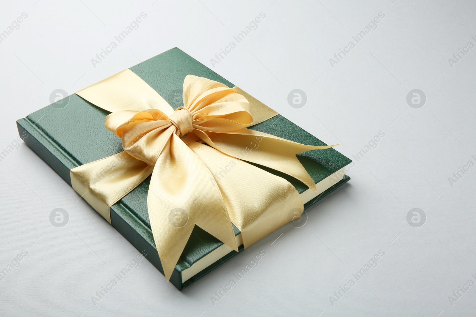 Photo of Book tied with golden ribbon on grey background. Perfect gift