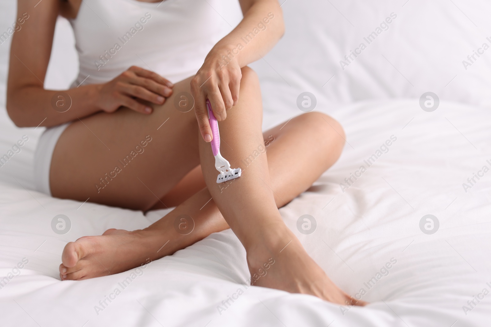 Photo of Woman shaving leg on bed, closeup. Depilation procedure