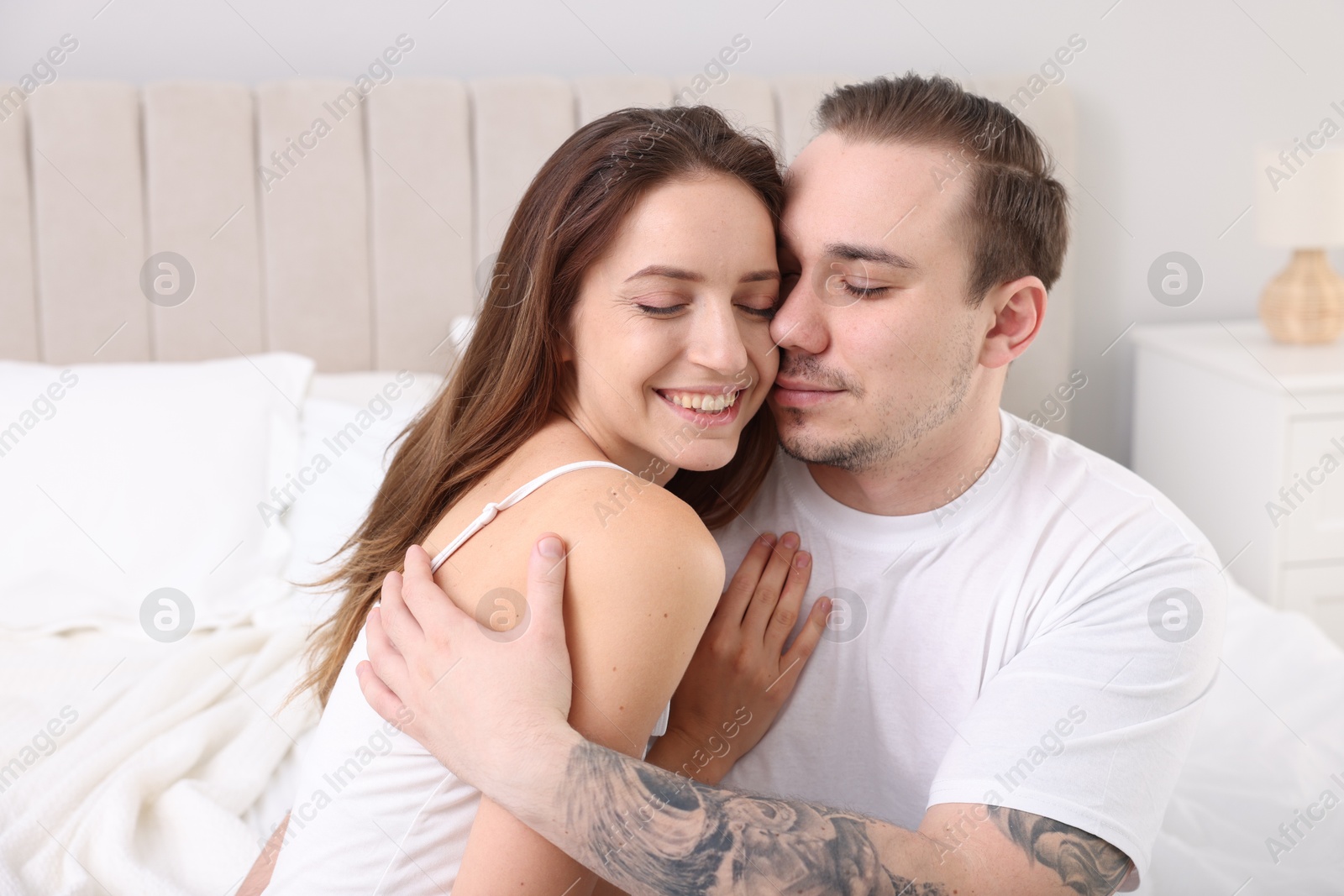 Photo of Happy couple spending time together on bed at home