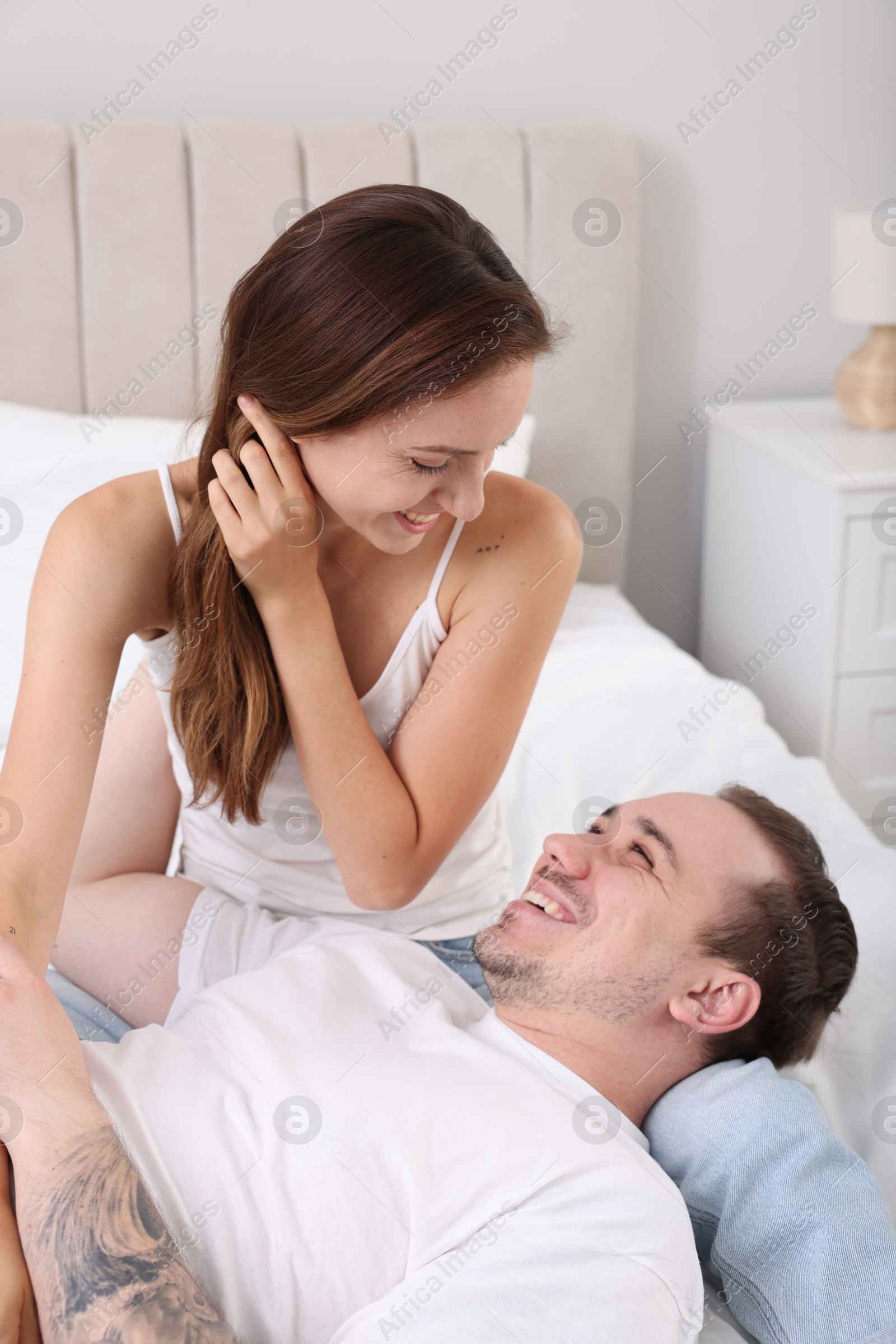 Photo of Happy couple spending time together on bed at home