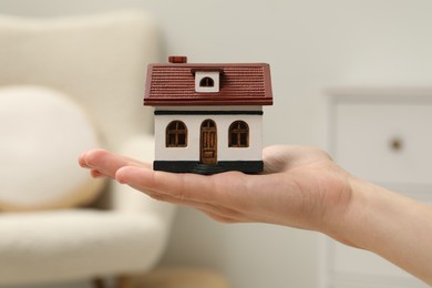 Woman holding house model at home, closeup