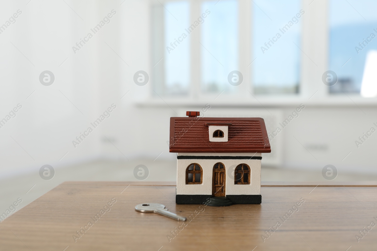 Photo of House model and key on wooden table indoors