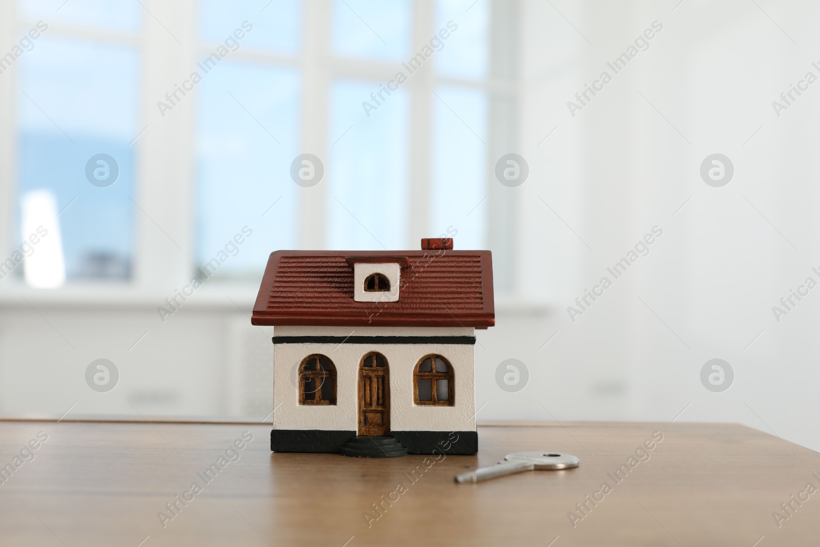 Photo of House model and key on wooden table indoors