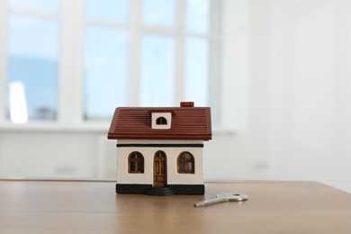 Photo of House model and key on wooden table indoors