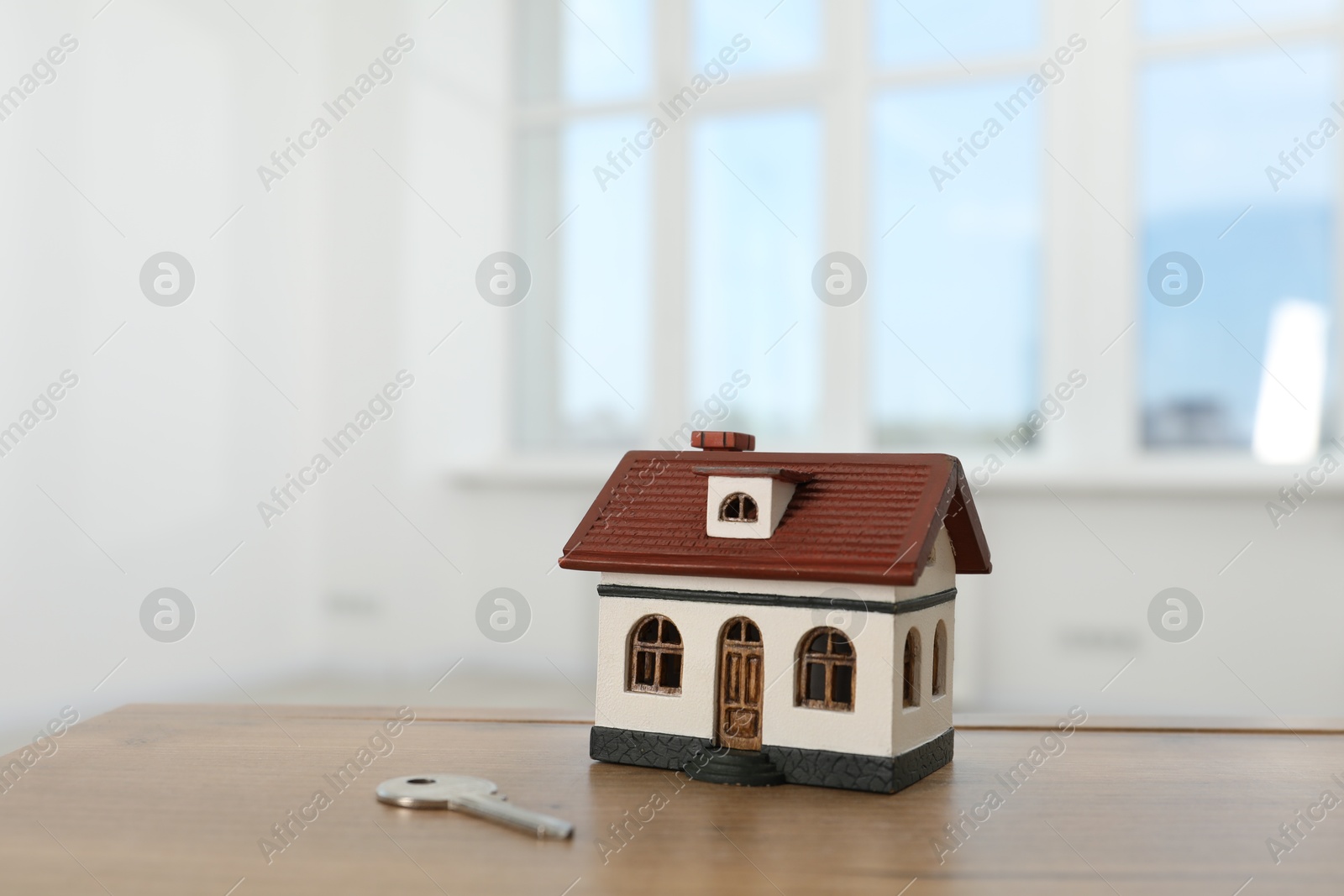 Photo of House model and key on wooden table indoors