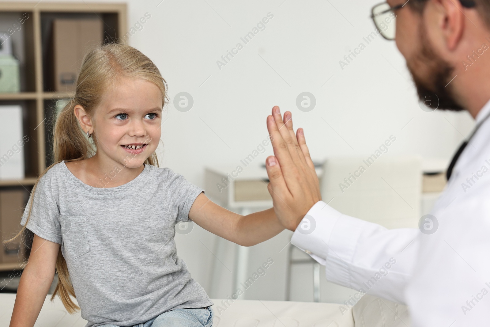 Photo of Doctor giving high five to little girl in hospital, closeup