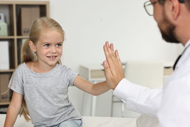 Doctor giving high five to little girl in hospital, closeup