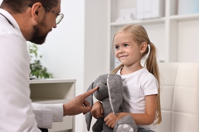 Photo of Little girl with toy having appointment with doctor in hospital