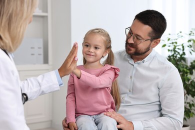 Little girl and her father having appointment with doctor in hospital