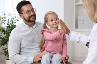 Little girl and her father having appointment with doctor in hospital