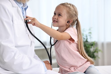 Photo of Little girl with stethoscope and doctor having fun in hospital