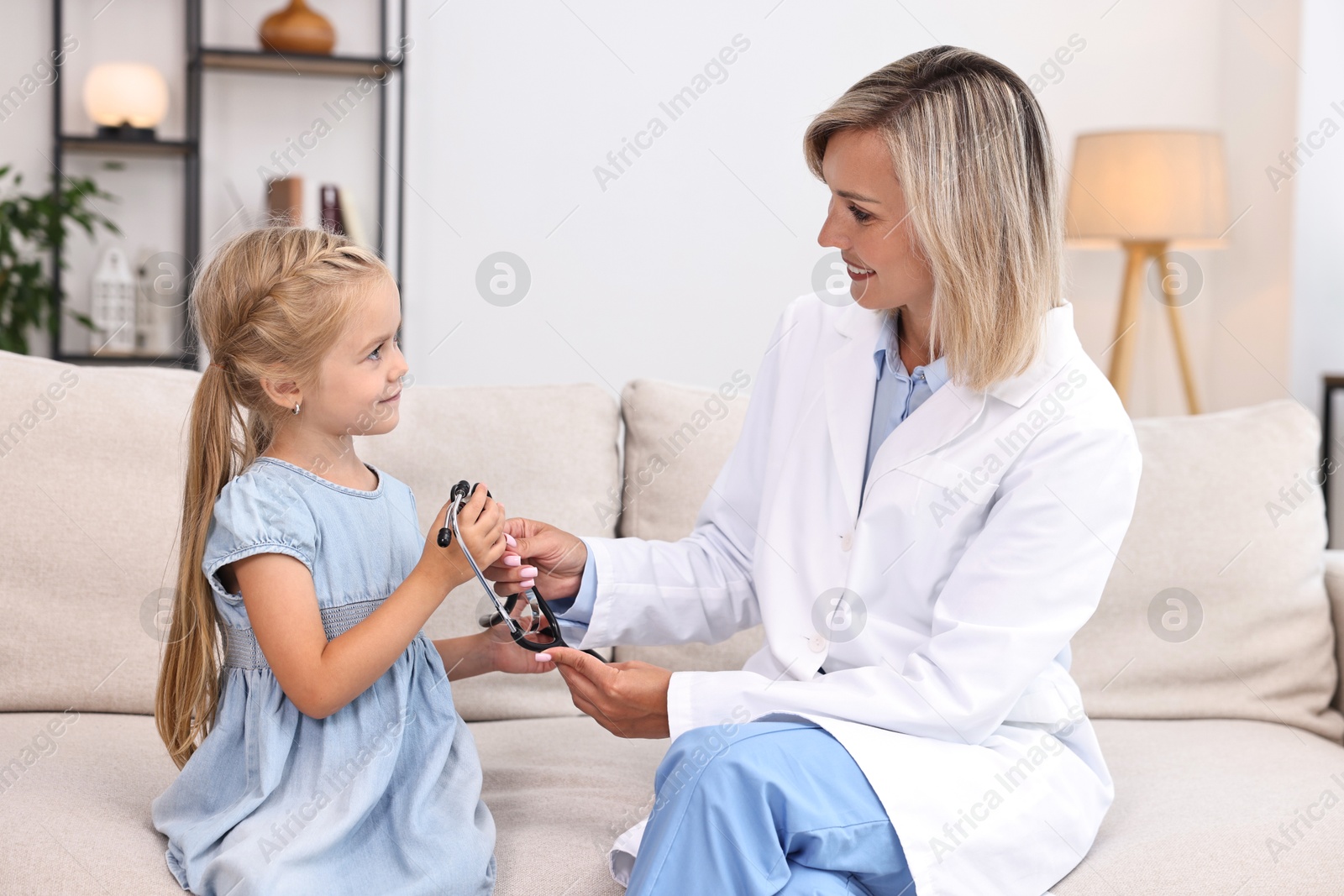 Photo of Doctor examining little girl with stethoscope indoors