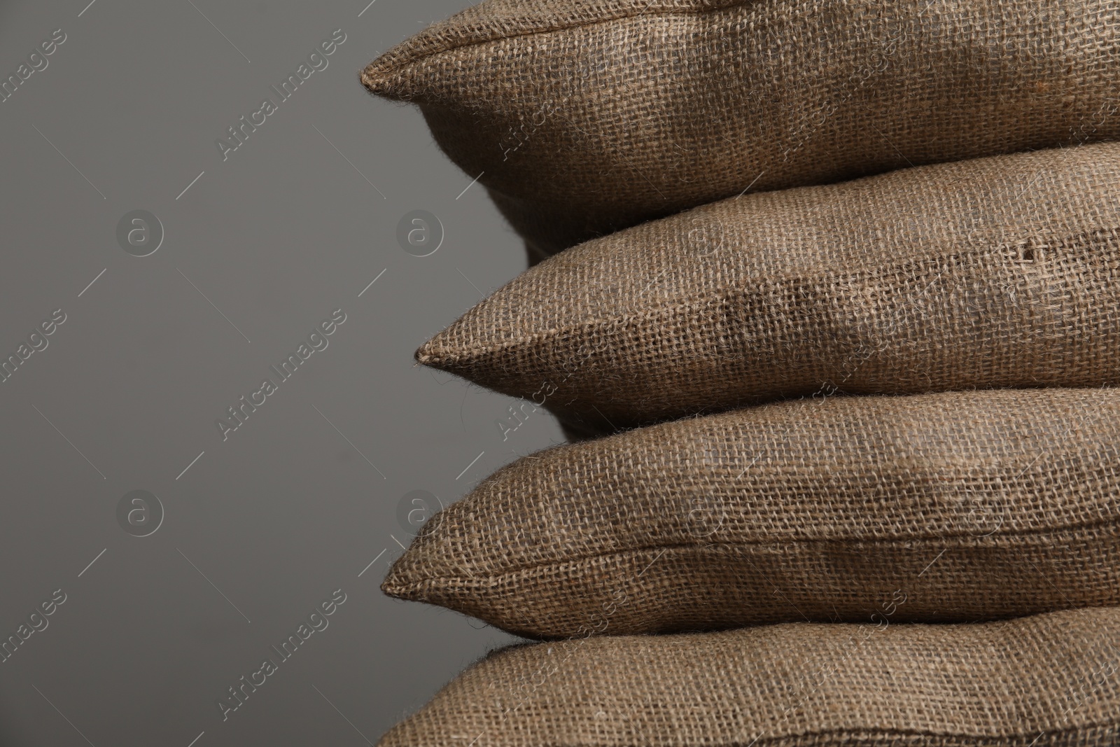 Photo of Group of burlap sacks on grey background, closeup. Space for text