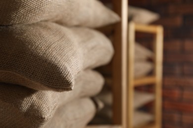 Group of burlap sacks on shelving unit indoors, closeup. Space for text