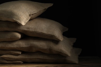 Group of burlap sacks on wooden table against black background