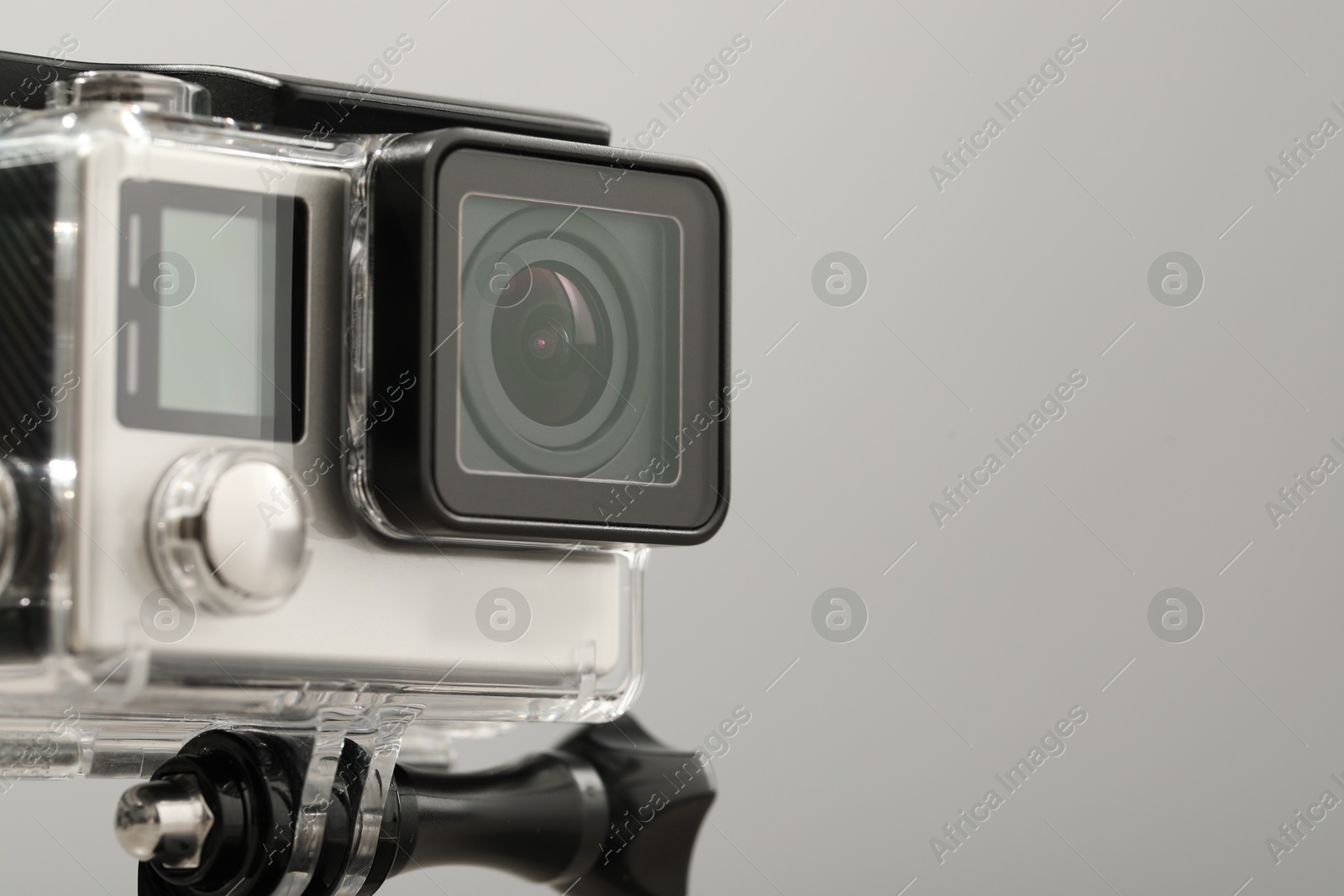 Photo of Modern action camera and mount on grey background, closeup. Space for text