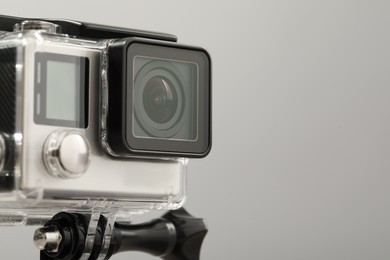 Photo of Modern action camera and mount on grey background, closeup. Space for text