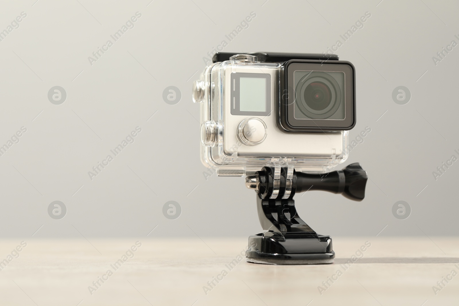 Photo of Modern action camera and mount on wooden table. Space for text