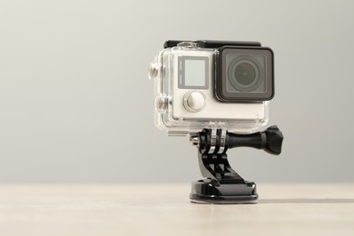 Photo of Modern action camera and mount on wooden table. Space for text