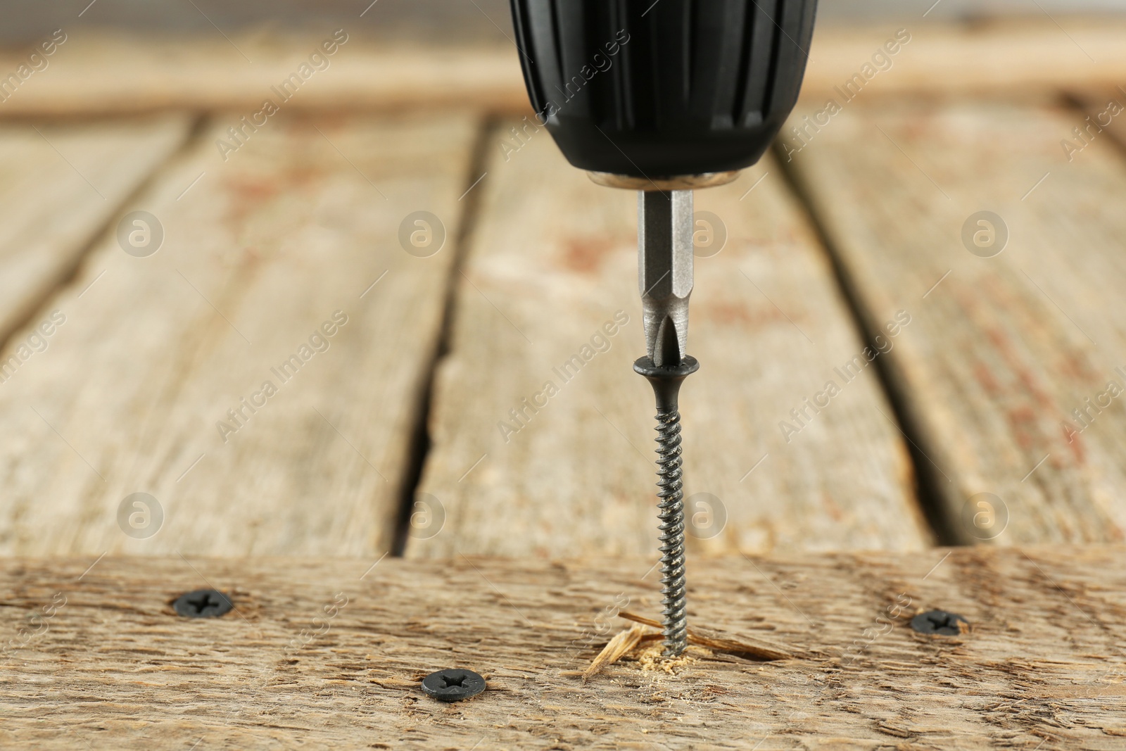 Photo of Screwing screw into wooden plank, closeup. Space for text