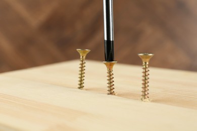 Photo of Screwing screw into wooden plank, closeup view