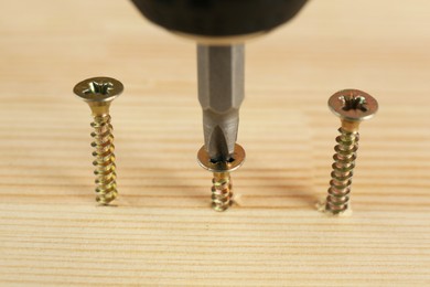 Photo of Screwing screw into wooden plank, closeup view